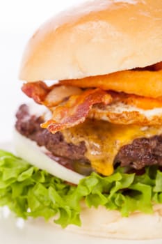 Delicious hamburger cheeseburger with bacon egg and salad on a plate isolated on a white background