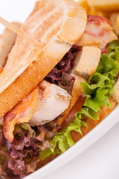 Club sandwich on toasted white bread with bacon and fries fried fries on a plate isolated against a white background