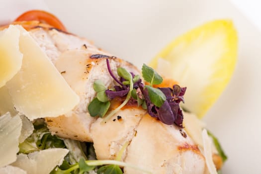 Fresh delicious caesarsalat with grilled chicken bust parmesan shards and croutons isolated against a white background