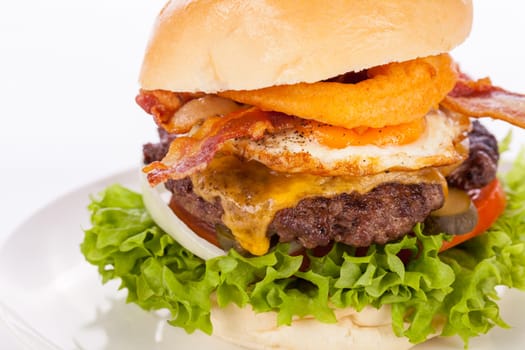 Delicious hamburger cheeseburger with bacon egg and salad on a plate isolated on a white background