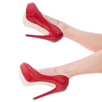 Sexy long legs of an attractive woman with red stilettos isolated against a white background