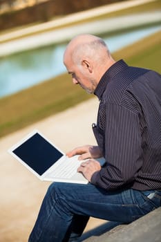 Businessman senior with notebook laptop during lunch break in summer outdoors
