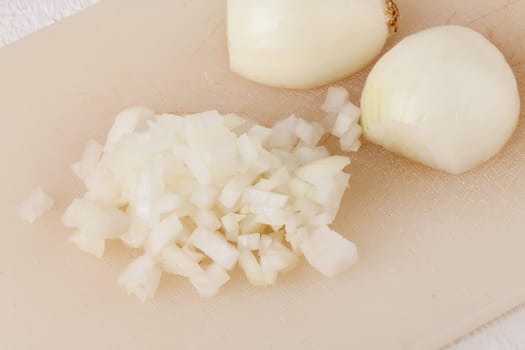 White and red onions peeled and with slurs as a whole and in cubebrunoise as a close-up on cutting board