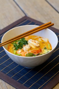 Bowl plate with freshly prepared Tom Yam soup with clanguste and coriander with chopsticks as close-up