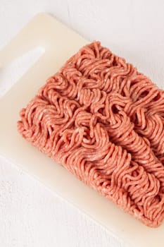 Minced meat raw beef and pork mixed as a block of protective atmosphere as a close-up on a white plate