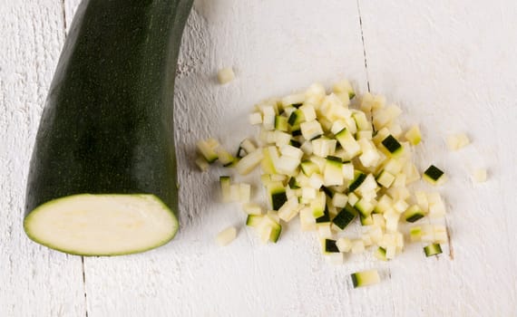 Fresh zucchini all in julienne strips and cut into brunoise cubes on a white hoözboard