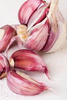 Garlic tuber with toes Fresh in whole and as a detail as a close-up on white wood