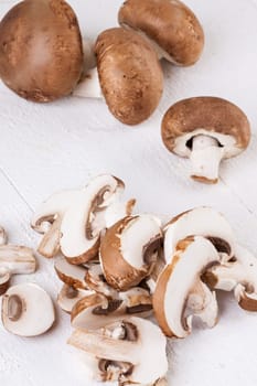 Fresh stone mushrooms Champiggnons whole and sliced on a white wooden board