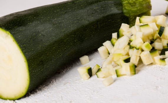 Fresh zucchini all in julienne strips and cut into brunoise cubes on a white hoözboard