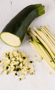 Fresh zucchini all in julienne strips and cut into brunoise cubes on a white hoözboard