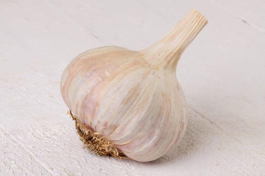 Garlic tuber with toes Fresh in whole and as a detail as a close-up on white wood