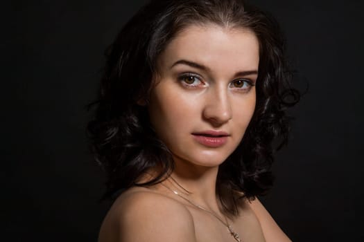 Young attractive woman with freckles in portrait against a black background