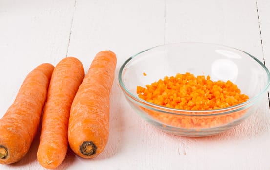 Fresh carrots beet root beet as whole and finely diced brunoise in a bowl on a white wooden board
