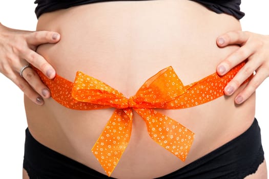 Young pregnant woman with orange bow around her belly as close-up isolated against white background