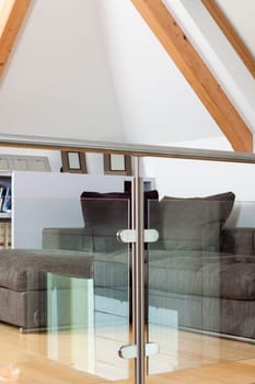 Living room with grey sofa behind a glazed railing in a property