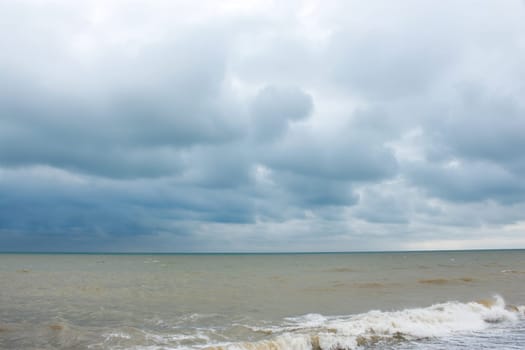 Sandy sea beach during strong wind, sea water mixed with sand and colored in yellow