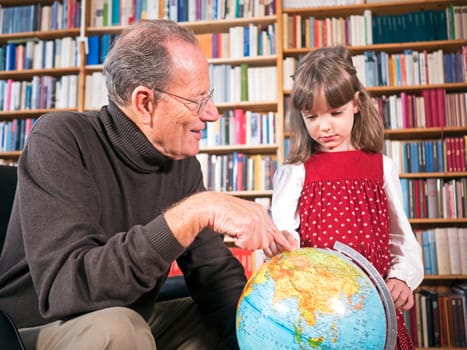 Grandfather and granddaughter look at a globe