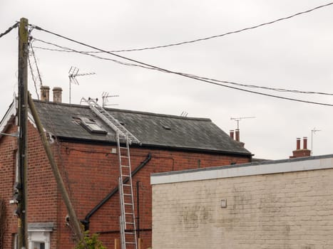 a ladder up the side of a house and along the roof construction no people or workers building roofers fixing holes repair