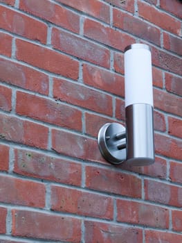 an outside metal and white modern lamp turned off not on near front door in the day light and on brick wall behind domestic cool silver