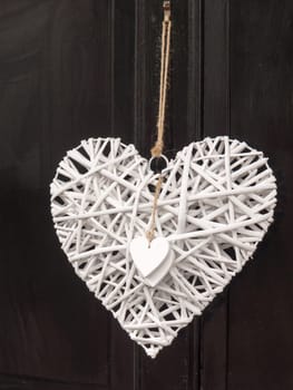 a modern and cool outside door decoration of a white love heart attached and hanging onto a black door homely private personal student rich love heart symbol
