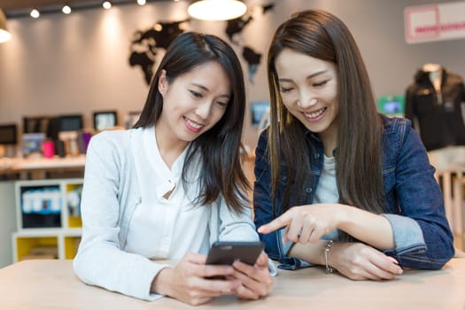 Happy women looking at mobile phone together