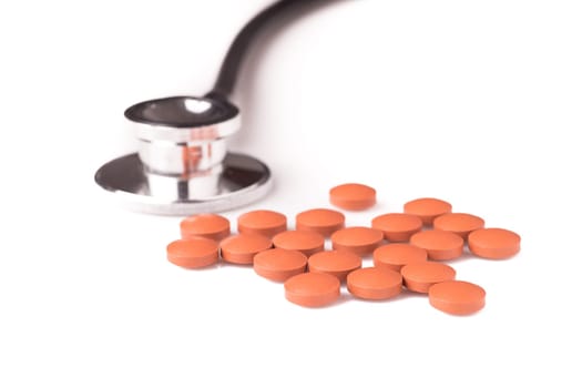 medicine and stethoscope. The stethoscope is next to the pills, isolated on white background