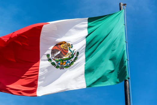 Closeup view of a Mexican flag waving in the wind as seen in Izamal, Mexico