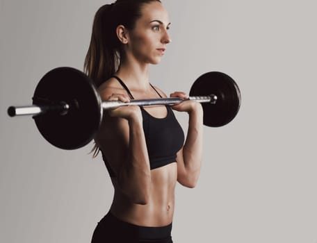 Shot of a beautiful young woman in a workout gear lifting weights