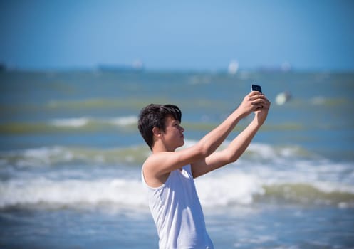 SCHEVENINGEN, NETHERLANDS - JULY 3, 2016: Unknown boy making a selfie for his girlfriend along the sea shore