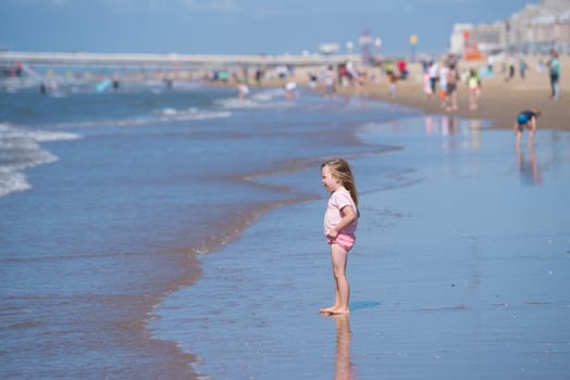 SCHEVENINGEN, NETHERLANDS - JULY 3, 2016: Unknown little girl enjoying the waves at the North sea beach