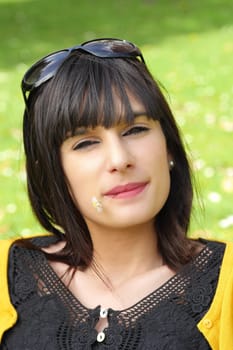 portrait of young brunette girl with a daisy in the mouth in the park, outdoors