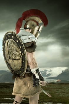 Ancient warrior or Gladiator posing with mountains in the background