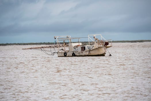 Fishing boat moving through the river on cloudy day