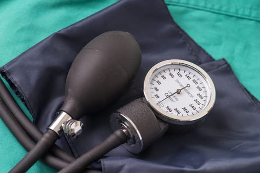 Blood pressure device located on the hospital green background. The background can be a textile part of a doctor or nurse's work uniform