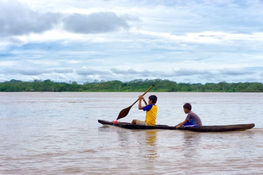 IQUITOS, PERU - MARCH 13: Two children navigate the Amazon River in a dugout canoe near Iquitos, Peru on March 13, 2015
