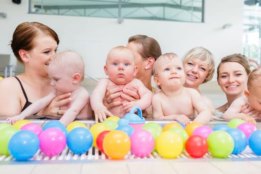 Group of moms and their little babies at baby swimming lesson