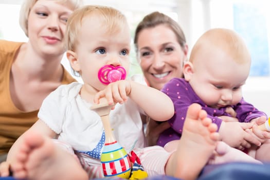 Babies with pacifier in toddler group playing with toys