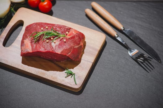 Raw beef on a cutting board  with spices and ingredients for cooking.
