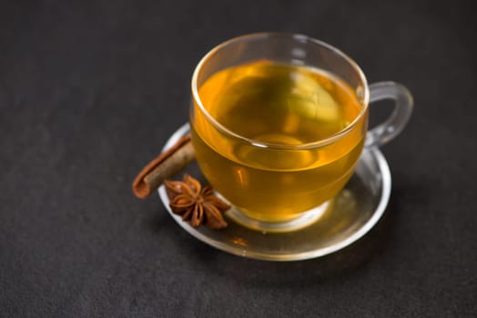 Cup of black tea with spices on white wooden background.