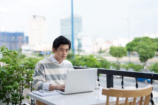 Asian young business man working with laptop at the city cafe.