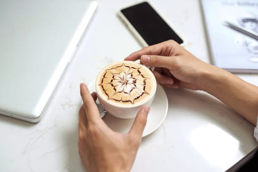 Asian businessman using mobile phone  during coffee break on table in coffee shop