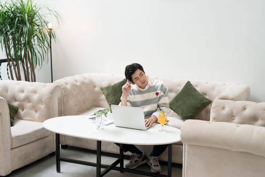 Asian young businessman working on his laptop in a coffee shop