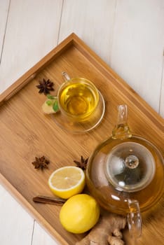 Cup of ginger tea with lemon and honey on white wooden background.