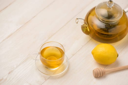 Cup of lemon tea with honey on white wooden background.