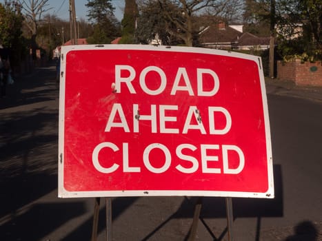 A a big red and white road closed ahead sign