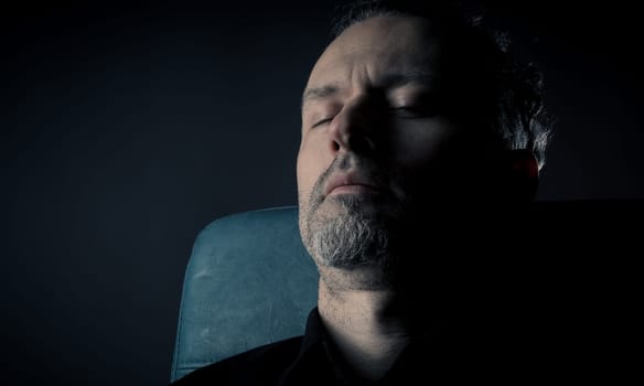 close up of a man sleeping on a leather chair