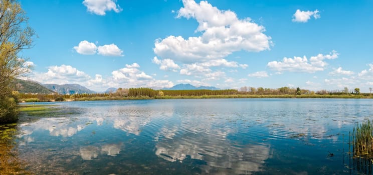 Landscape with lake,forest,blue sky and cloud.   Man fishing from the shore of lake .
