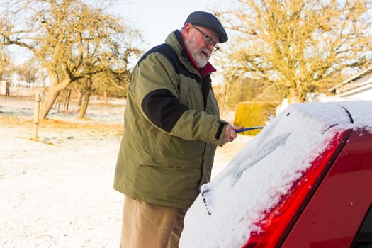 Senior frees car window from frost and snow