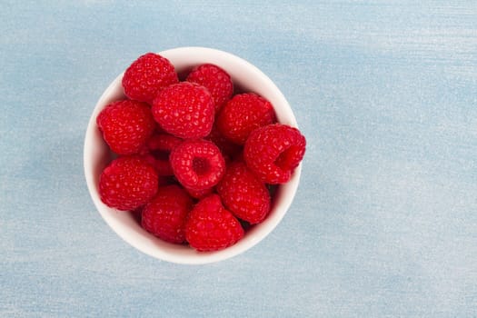 Fresh raspberries on a light blue background