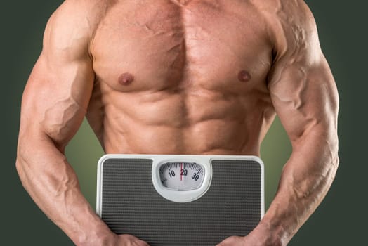 Powerful athletic man with great physique holding a weight scale.